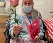 older adult holding a valentine card and rose